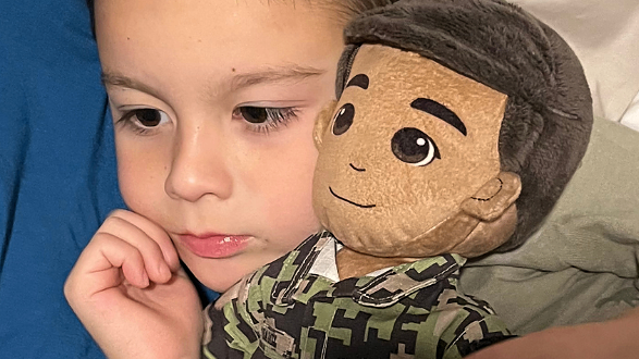 Child holding a plush toy with a neutral expression