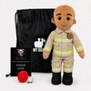 A firefighter-themed plush doll stands in front of a black drawstring bag, with a black card reading 'UMBO' and a red hose coil on a white studio background.