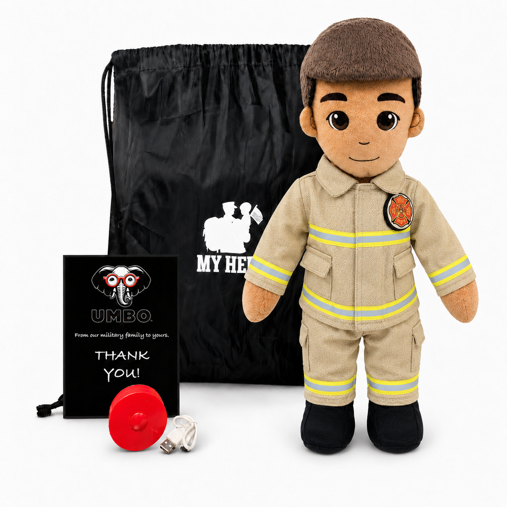 A plush firefighter doll stands in front of a black drawstring bag, with a small black card and a red fire helmet on a white studio background. The doll wears a tan firefighter uniform with yellow reflective stripes, black boots, and a brown cap.