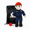 A plush toy dressed as a police officer stands in front of a black drawstring bag. The doll wears a red beret, dark blue uniform, black boots, and has a red badge on the chest.