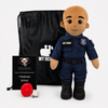 A personalized plush police officer dressed in a navy blue uniform with black boots and a black drawstring bag, shown with a small black card and a red round on a light gray background.