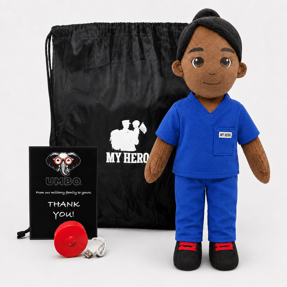 Nurse doll in blue medical scrubs with dark skin and black hair, female recordable medical plush doll. A plush doll dressed in blue medical scrubs stands in front of a black drawstring bag and a black card that reads 'MY HERO' with a soldier silhouette. The bag and card also show the UMBQ logo, and a small red ribbon and white tissue are placed on the floor.