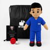 A plush toy soldier dressed in blue medical scrubs stands in front of a black drawstring bag and a small black gift card. The bag and card both show the text 'MY HERO' and a white silhouette of a soldier, and the toy has a small chest patch reading 'MY HERO'.