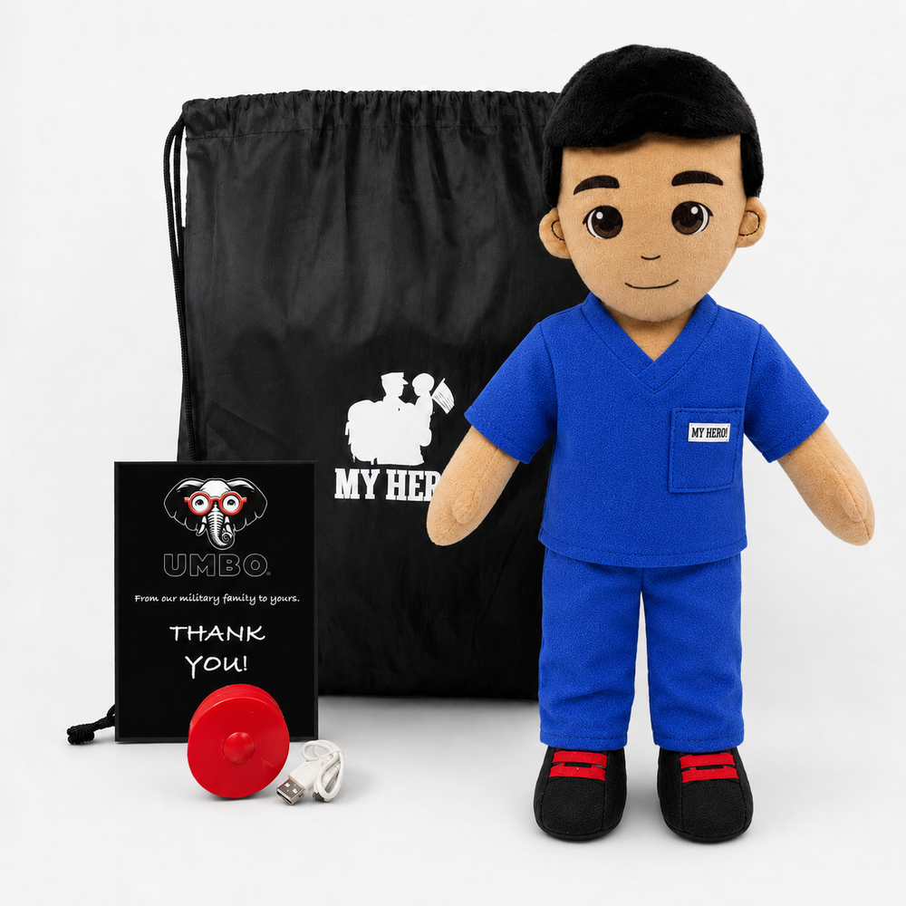 A plush toy soldier dressed in blue medical scrubs stands in front of a black drawstring bag and a small black gift card. The bag and card both show the text 'MY HERO' and a white silhouette of a soldier, and the toy has a small chest patch reading 'MY HERO'.