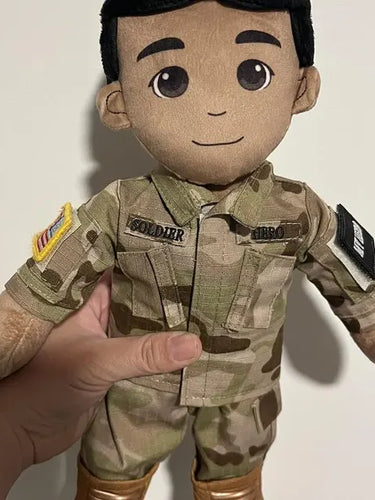 Plush toy in a military uniform held by a hand against a plain background