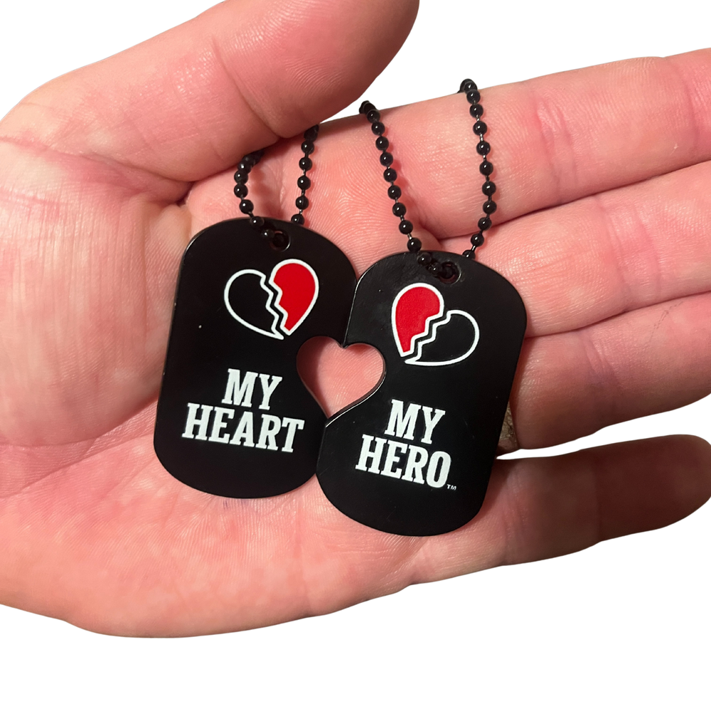 Two black heart-shaped dog tags on a bead chain with a white-and-red broken-heart emblem.