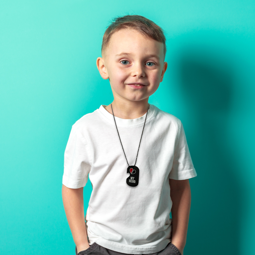 Boy wearing matching deployment dog tag set on black cord with 'My Hero' tag.